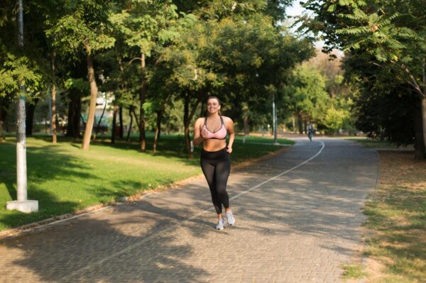 running for weight loss - Overweight woman jogging outdoors with confidence and a smile, finding strength through running