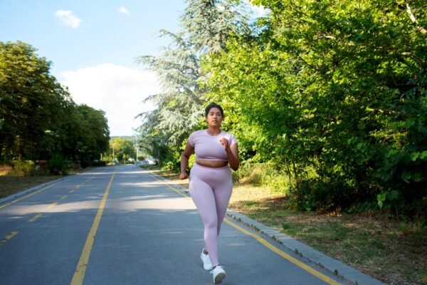 Overweight woman running on a sunny trail, beginning her fitness journey for weight loss