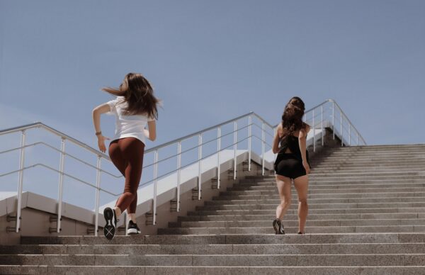 Running style - two women strengthen their muscles running up a stair