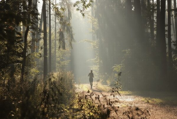 Runner on a forest trail during sunrise reflecting during outdoor running