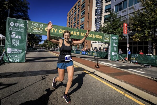 finish a marathon - Woman cheering after passing the marathon finish line