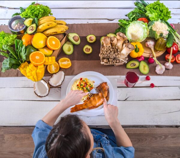 a runners diet - Woman at the dining table with a variety of organic healthy food for runners.