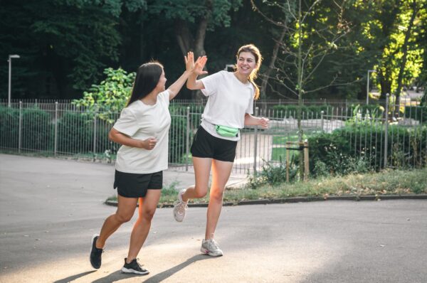 how to start running - two beginner runners jogging together making high five