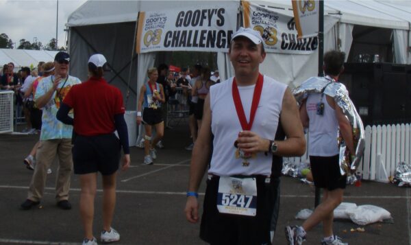 Recover post marathon - Smiling runner in a reflective moment with medal in hand