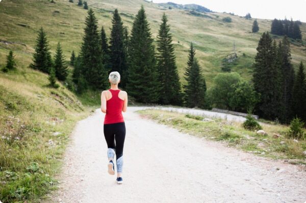 marathon training plan - young woman running on a trail road