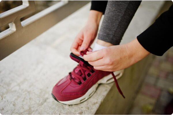 running for beginners - A young girl laces her new running shoes before running