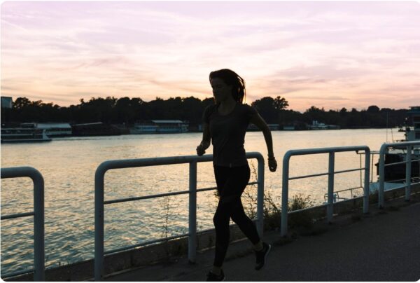 running for beginners - Sunset silhouette of a runner alone along a river