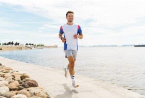 A fit man jogs along a sunny waterfront path embodying vitality and health