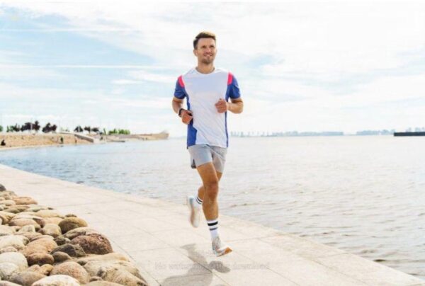 A fit man jogs along a sunny waterfront path embodying vitality and health