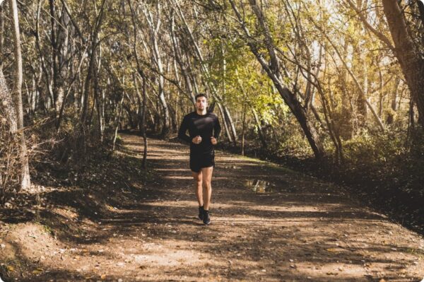 Focused runner alone on a forest trail creating ideal conditions for flow and concentration