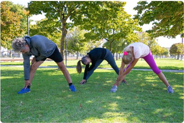 Three people stretching before a run in a park