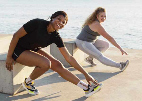 Two women stretching before a run by the water