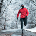 Winter running exercise, runner on road in snowy forest
