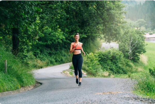 proper running form - woman running on a road with trees around her