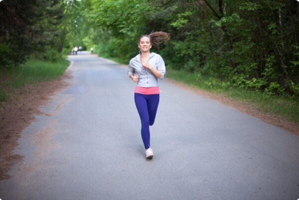 training zones - A Happy young woman running in zone 3 and smiling in park