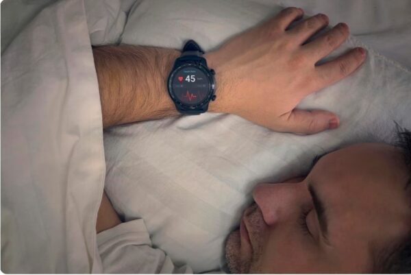 training zones - A man sleeps early in the morning with a HRM Watch on his wrist sshowing his heart rate