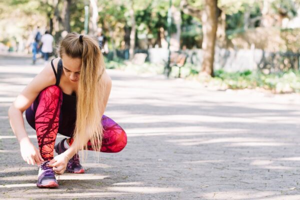 Woman tying laces on a park alley, ready to a run