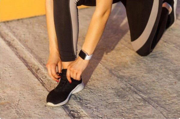 Runner’s hands tying shoes, watch ready to start long run timer