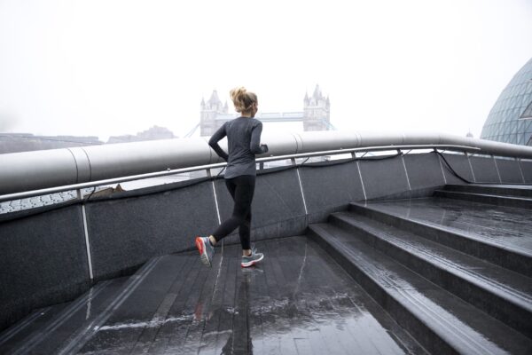 marathon training motivation - Woman running in the city streets while it rains