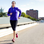 Pretty young woman running in city.